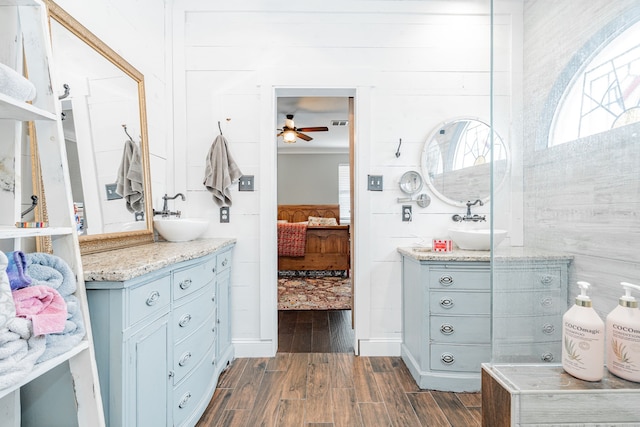 bathroom featuring wooden walls, hardwood / wood-style floors, vanity, and ceiling fan