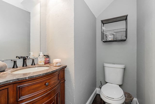 bathroom featuring vanity, vaulted ceiling, and toilet