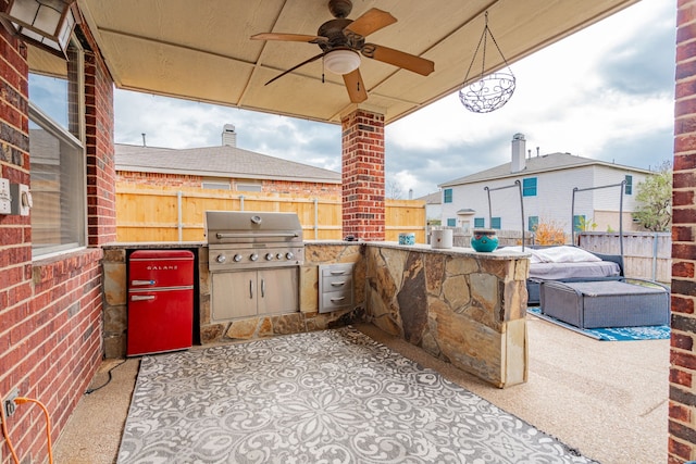 view of patio with area for grilling, ceiling fan, and exterior kitchen