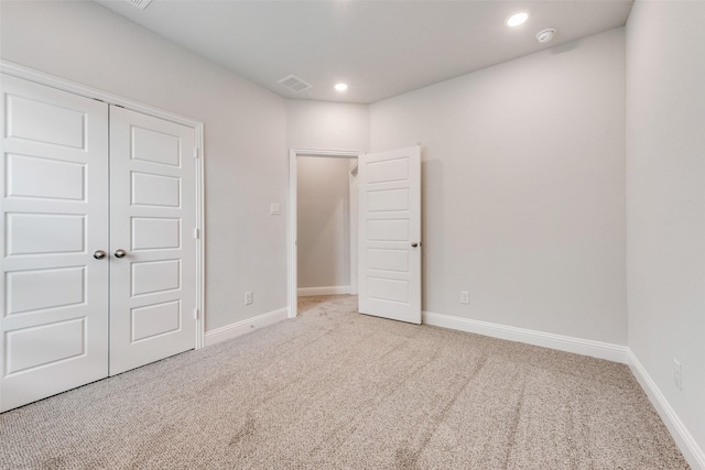 unfurnished bedroom featuring light carpet and a closet