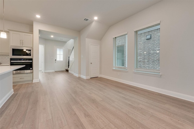 kitchen featuring decorative light fixtures, built in microwave, light hardwood / wood-style floors, and stainless steel oven