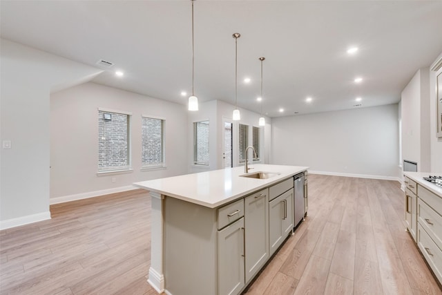 kitchen featuring dishwasher, light wood-type flooring, sink, and an island with sink