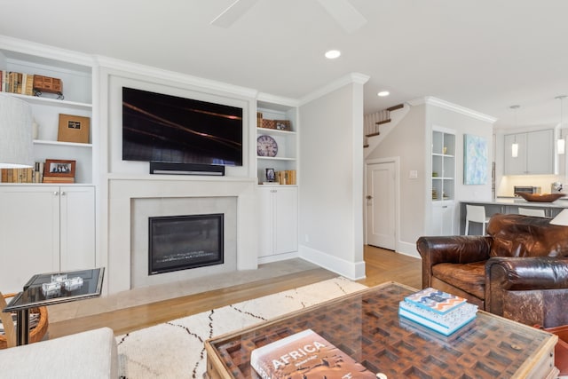 living room featuring crown molding, built in features, and light hardwood / wood-style flooring