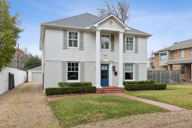 view of front of house with a garage, an outbuilding, and a front lawn