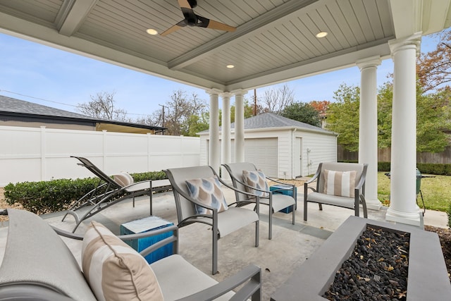 view of patio / terrace featuring an outbuilding, a garage, ceiling fan, and an outdoor fire pit