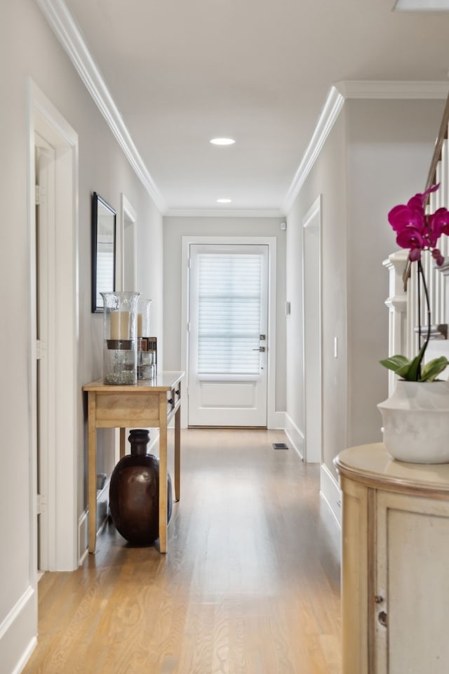 doorway with ornamental molding and light wood-type flooring