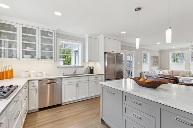 kitchen with stainless steel appliances, sink, white cabinets, and decorative light fixtures