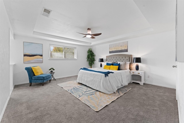 bedroom featuring carpet flooring, a tray ceiling, and ceiling fan