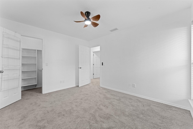 unfurnished bedroom featuring a closet, light colored carpet, and ceiling fan