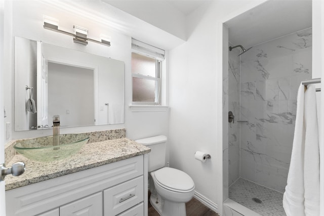 bathroom featuring a tile shower, vanity, and toilet