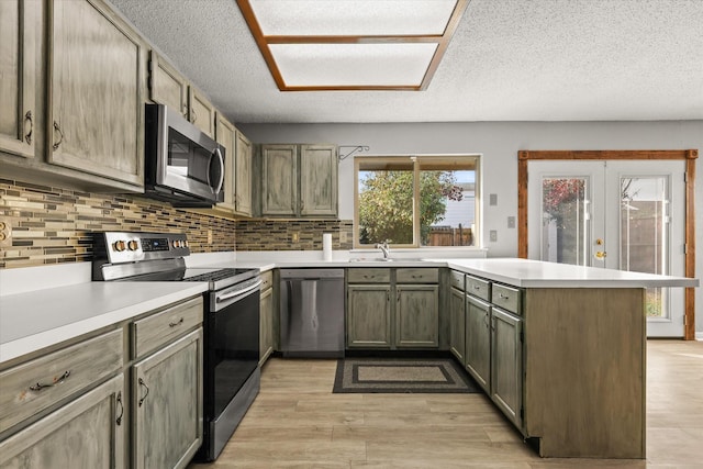 kitchen featuring stainless steel appliances, tasteful backsplash, light hardwood / wood-style flooring, kitchen peninsula, and a textured ceiling