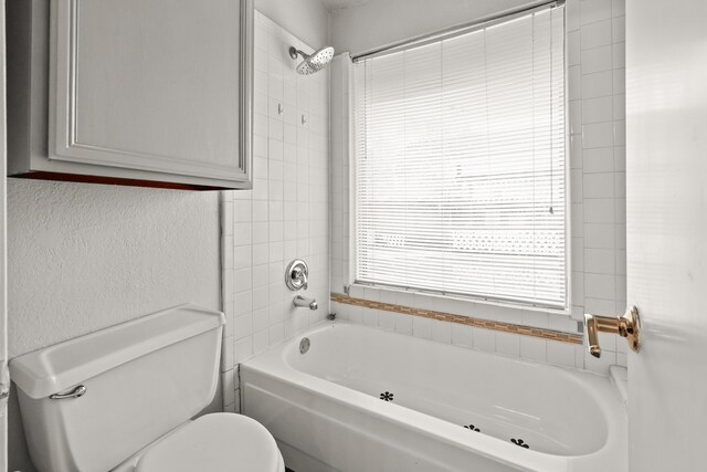 bathroom featuring toilet and tiled shower / bath