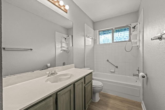 full bathroom with tiled shower / bath, hardwood / wood-style floors, vanity, and toilet