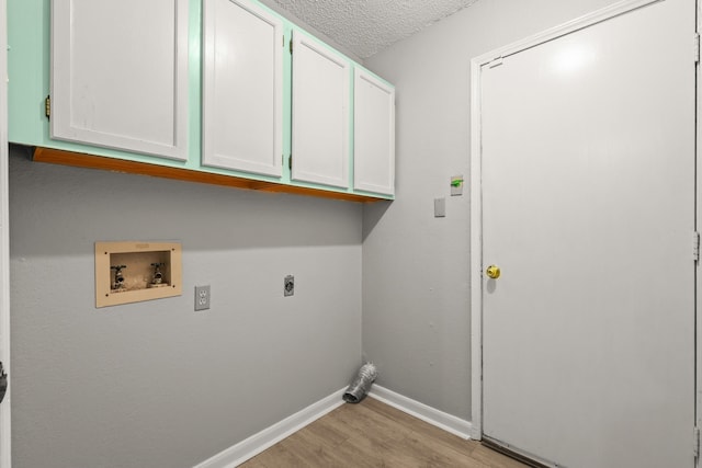 clothes washing area featuring electric dryer hookup, cabinets, light hardwood / wood-style flooring, washer hookup, and a textured ceiling