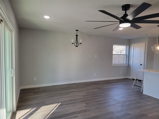 interior space with ceiling fan with notable chandelier, dark hardwood / wood-style floors, and a textured ceiling