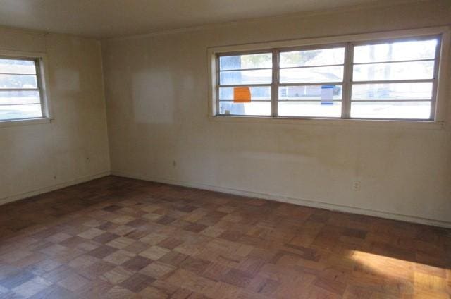 unfurnished room featuring dark parquet flooring and a wealth of natural light