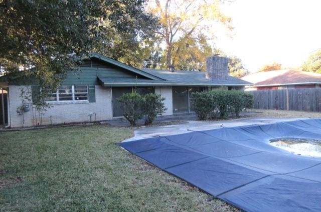 back of house with a yard and a covered pool