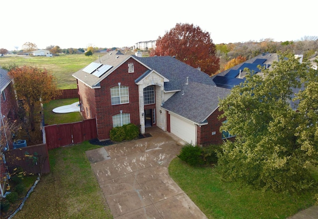 front facade featuring solar panels, a garage, and a front yard