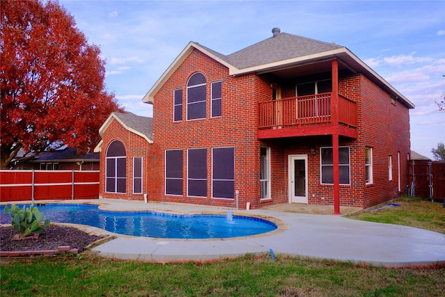 rear view of house with pool water feature, a balcony, a fenced in pool, and a patio