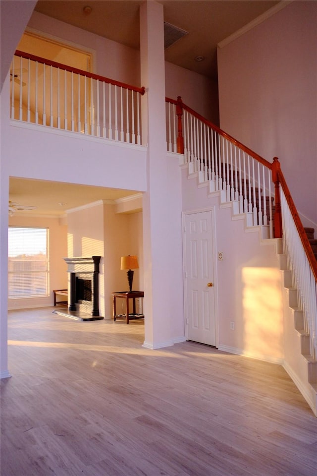 stairs featuring a towering ceiling, hardwood / wood-style flooring, and crown molding