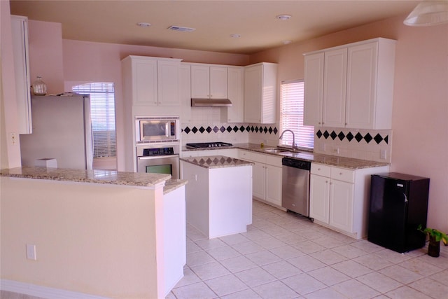 kitchen featuring tasteful backsplash, kitchen peninsula, stainless steel appliances, light stone countertops, and white cabinets