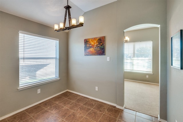 carpeted empty room with an inviting chandelier and a healthy amount of sunlight