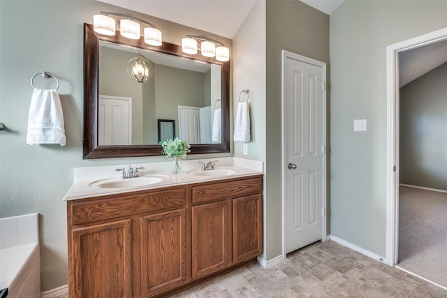 bathroom with vanity, a relaxing tiled tub, and an inviting chandelier