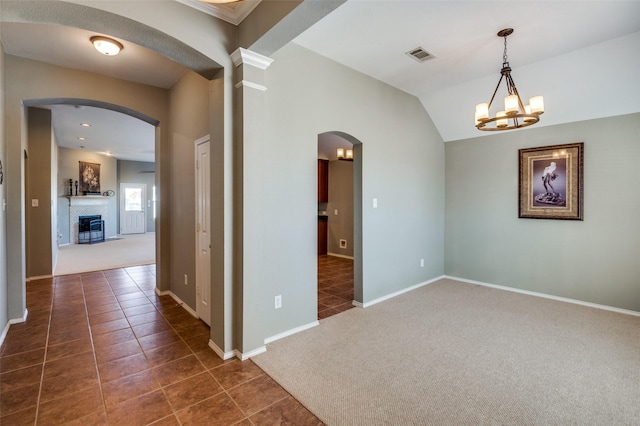 carpeted empty room with ornate columns, lofted ceiling, and a notable chandelier