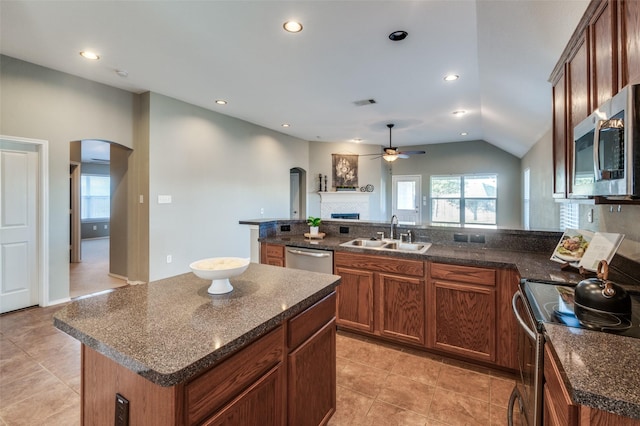 kitchen with ceiling fan, sink, a center island, vaulted ceiling, and appliances with stainless steel finishes