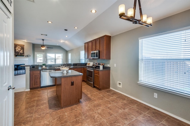 kitchen with ceiling fan with notable chandelier, sink, vaulted ceiling, kitchen peninsula, and stainless steel appliances