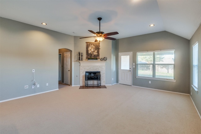 unfurnished living room featuring ceiling fan, lofted ceiling, light carpet, and a tiled fireplace