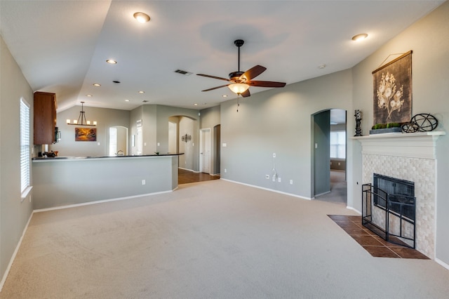 carpeted living room featuring a fireplace and ceiling fan with notable chandelier