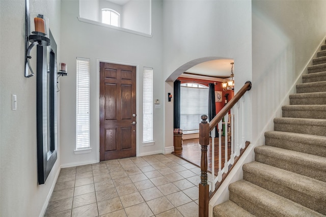 tiled foyer entrance featuring a high ceiling and an inviting chandelier