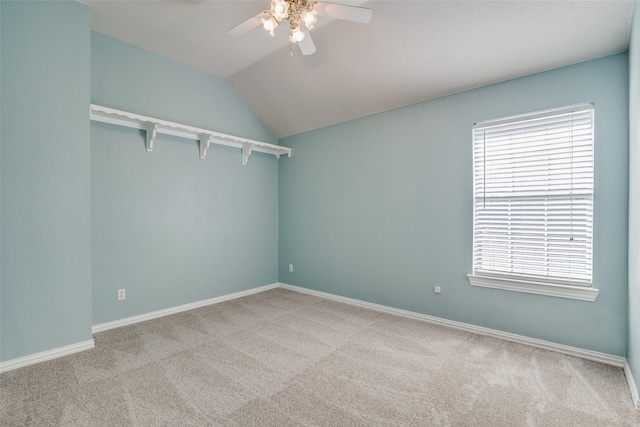 carpeted spare room with ceiling fan and vaulted ceiling