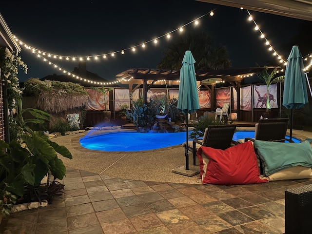 pool at night with a pergola and a patio area