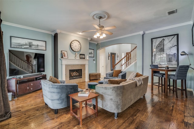 living room featuring a tile fireplace, crown molding, and hardwood / wood-style floors