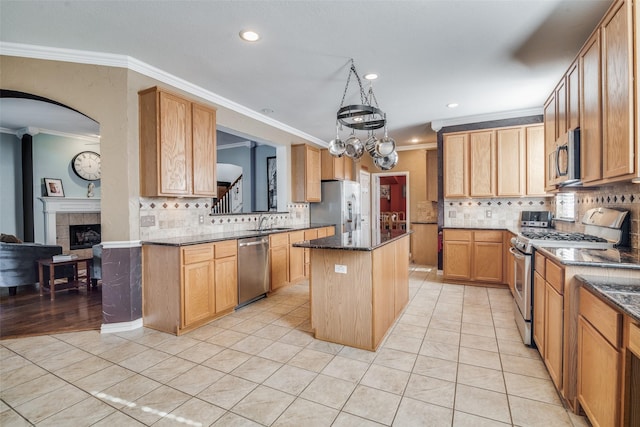 kitchen featuring appliances with stainless steel finishes, a kitchen island, crown molding, and dark stone countertops