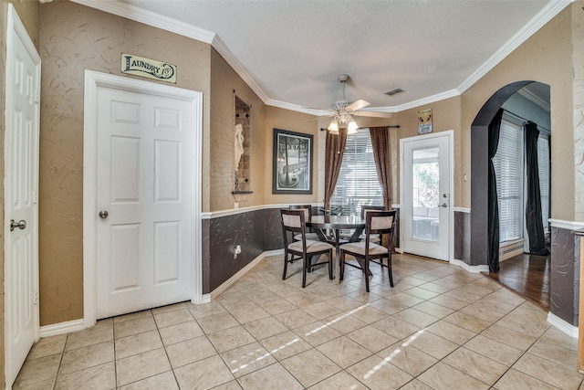 tiled dining space featuring ceiling fan and crown molding