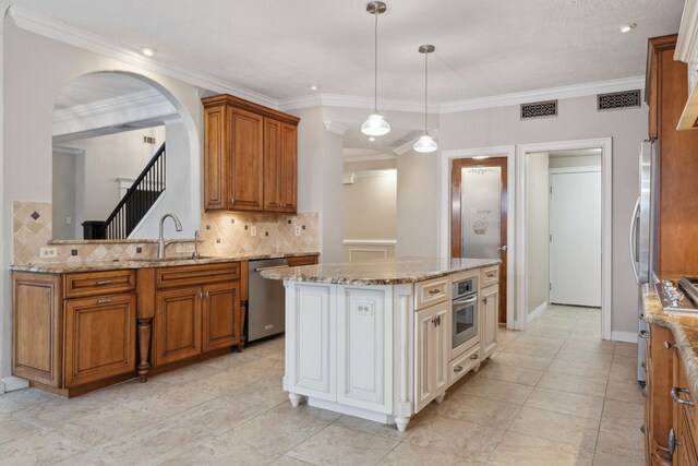 kitchen with decorative backsplash, appliances with stainless steel finishes, sink, a center island, and hanging light fixtures