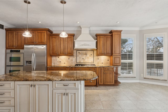 kitchen with decorative light fixtures, a center island, premium range hood, and appliances with stainless steel finishes