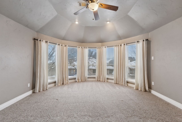 carpeted empty room with ceiling fan, plenty of natural light, and vaulted ceiling