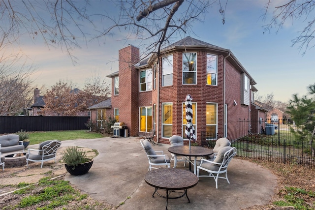 back house at dusk with a patio, a fire pit, and a lawn