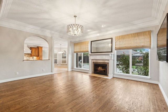 unfurnished living room with wood-type flooring, crown molding, and a notable chandelier