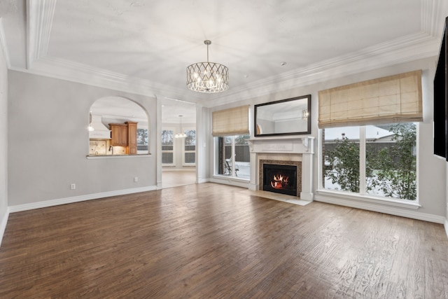 unfurnished living room with a fireplace, hardwood / wood-style floors, a chandelier, and ornamental molding