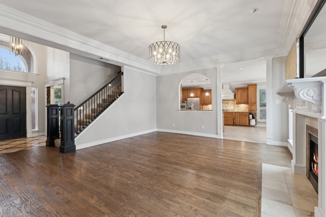 unfurnished living room with crown molding, a healthy amount of sunlight, and a notable chandelier