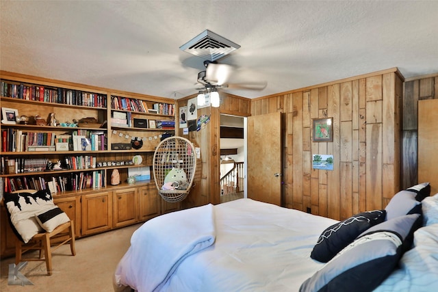 bedroom with light carpet, wooden walls, and a textured ceiling