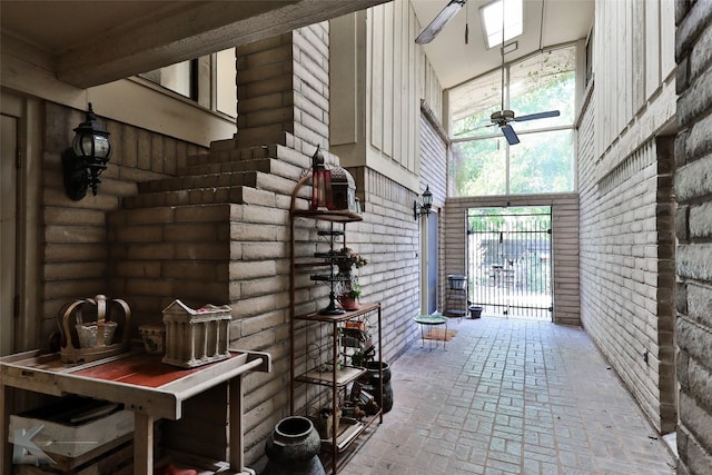 interior space with a high ceiling, brick wall, and ceiling fan