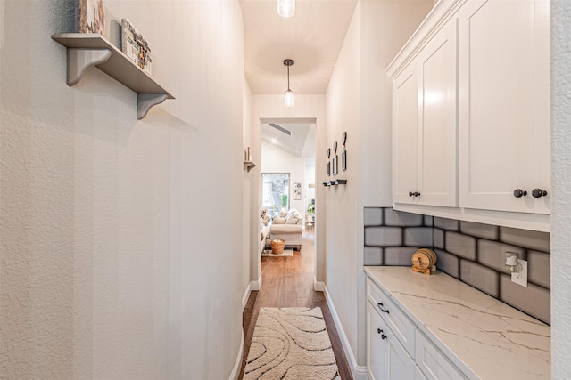 corridor with vaulted ceiling, baseboards, and wood finished floors