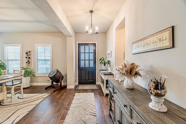 foyer entrance with baseboards, a chandelier, and dark wood-style flooring