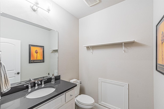 bathroom with vanity, toilet, and visible vents